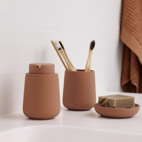 Seifenspender, Seifenschale, Zahnputzbecher und Handtuch in Orange.