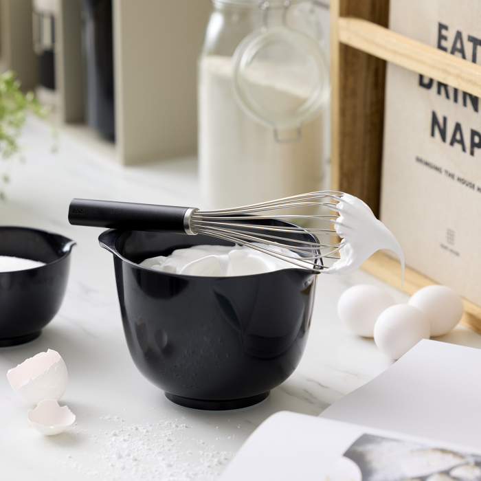 Schwarzer Rührbecher mit Eischnee und passendem Schneebesen.