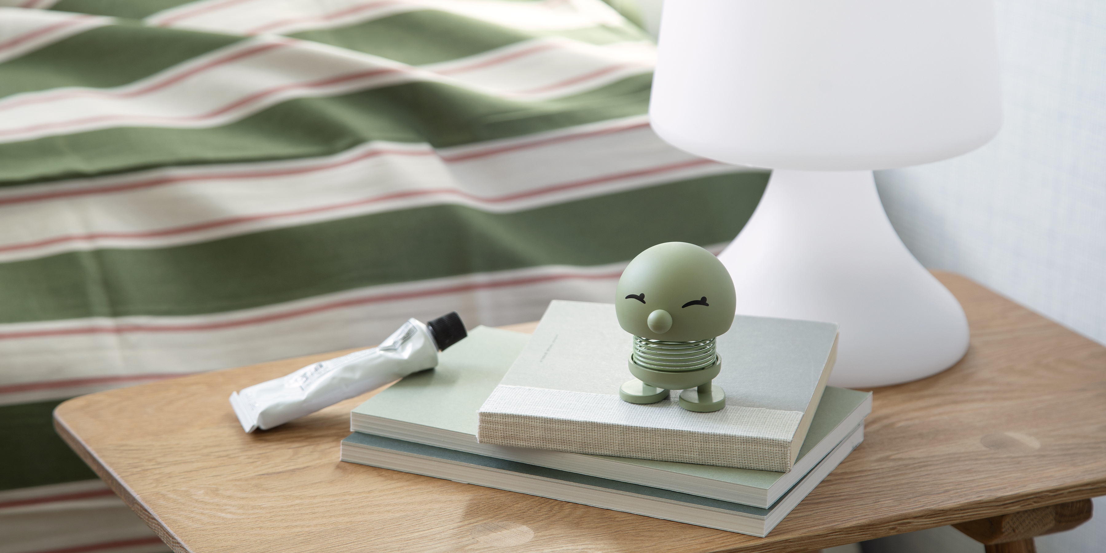 Pastellgrüner Hoptimist steht auf Büchern auf einem Nachttisch. Pastellgrüner Hoptimist steht auf Büchern auf einem Nachttisch.